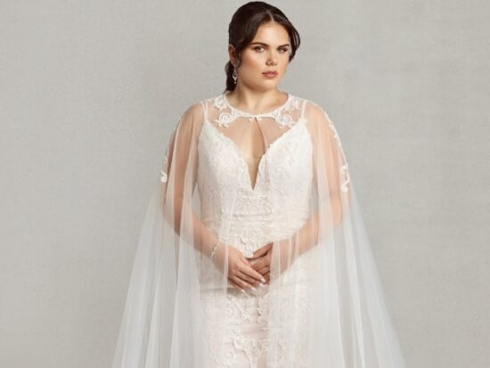 Bride wearing the "Dramatic Cape," a floor-length lace cape that acts as an alternative to a traditional bridal veil