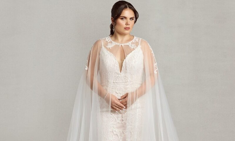 Bride wearing the "Dramatic Cape," a floor-length lace cape that acts as an alternative to a traditional bridal veil