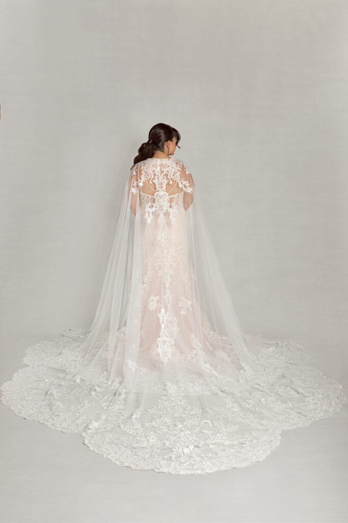 Bride wearing the "Dramatic Cape," a floor-length lace cape that acts as an alternative to a traditional bridal veil