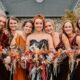 bride and bridesmaids smiling and holding striking bouquets of autumnal flowers and fall-themed dresses