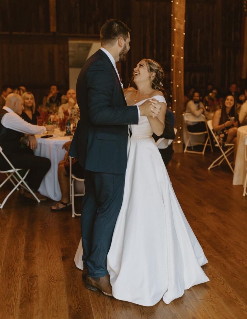 husband and wife sharing a first dance in an autumn-themed lodge lit with twinkling lights in Michigan