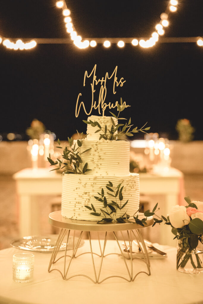 a gorgeous white wedding cake with gold and green detailing with autumn elements