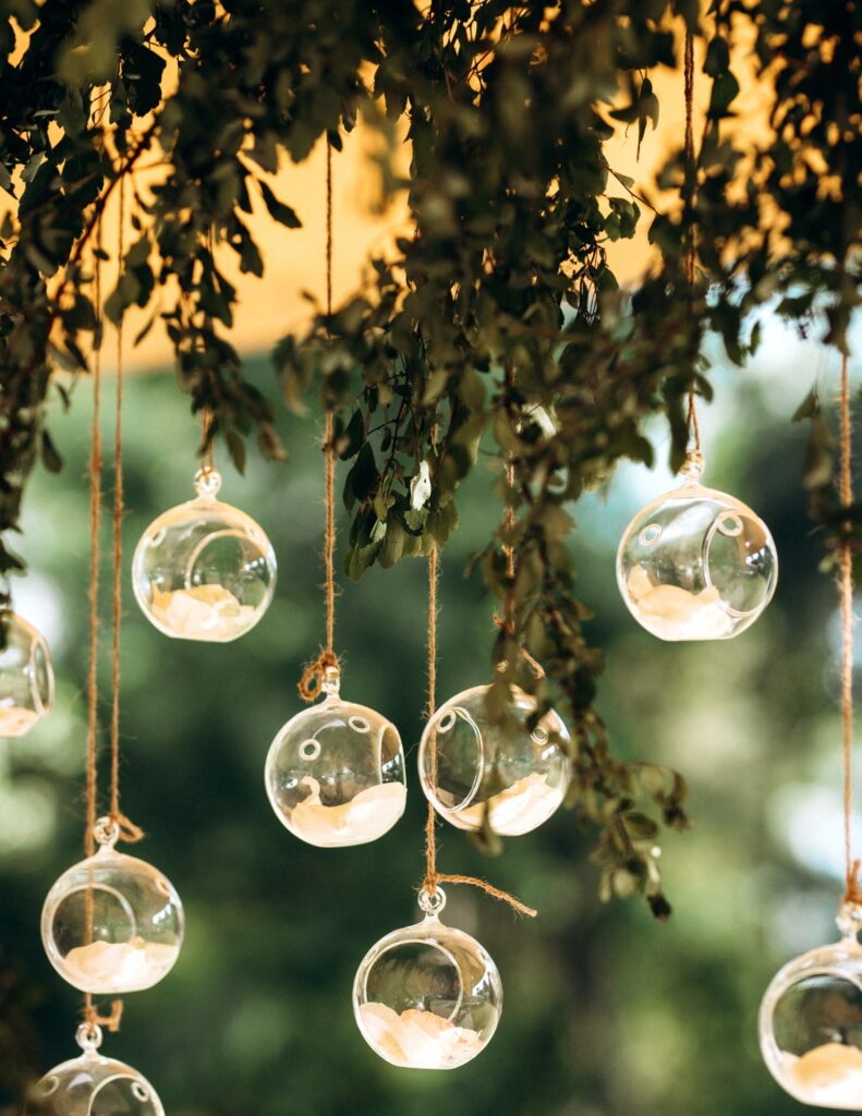 glass baubles with flower petals inside hanging from a tree attached by twine