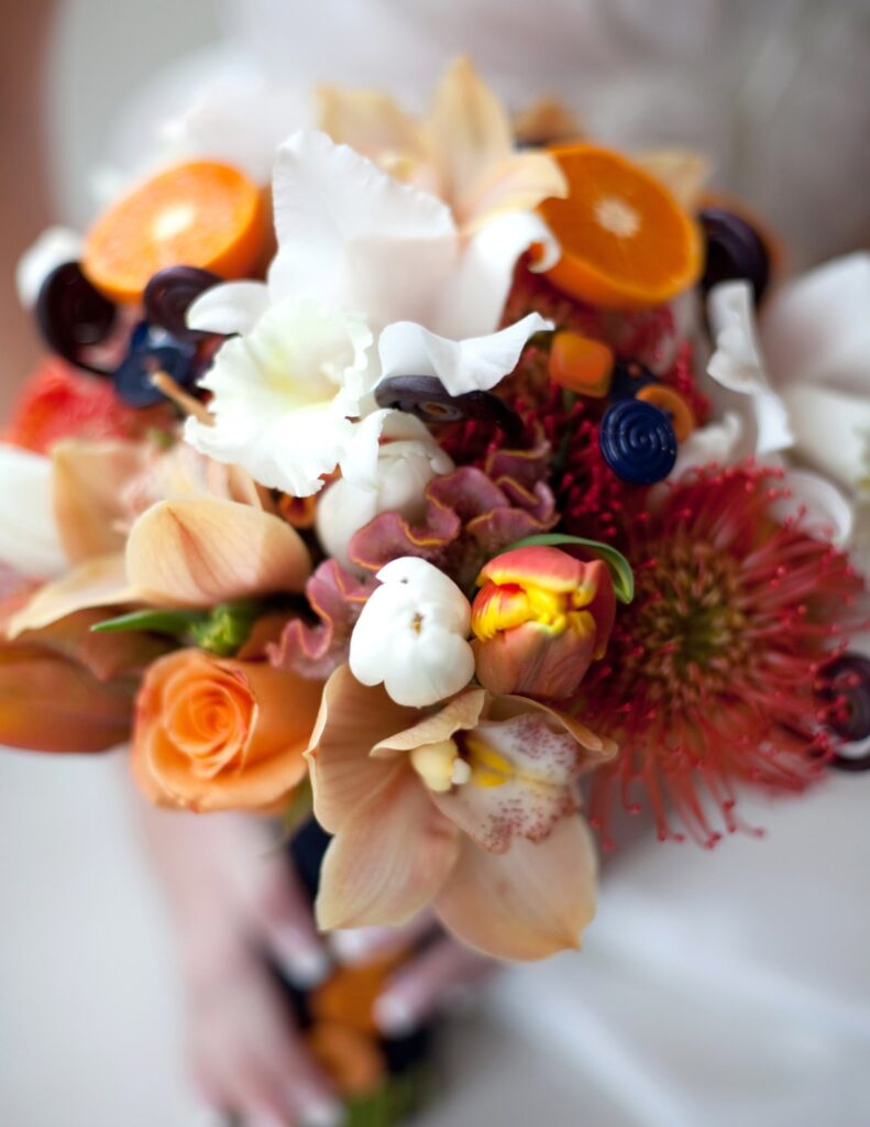 a fall-inspired wedding bouquet with white, orange, and red floral accents