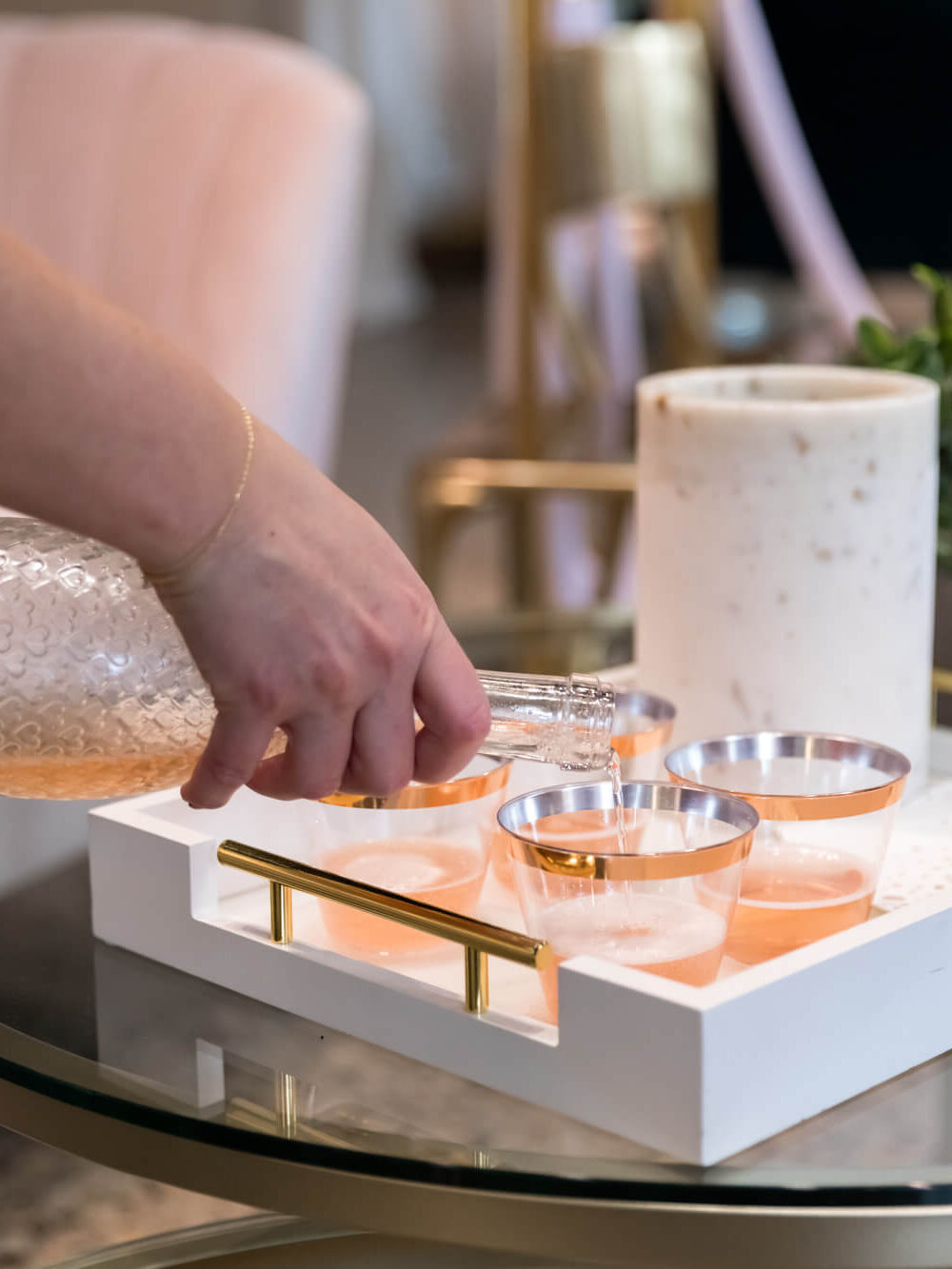 white rose wine being poured into small glasses in serving tray