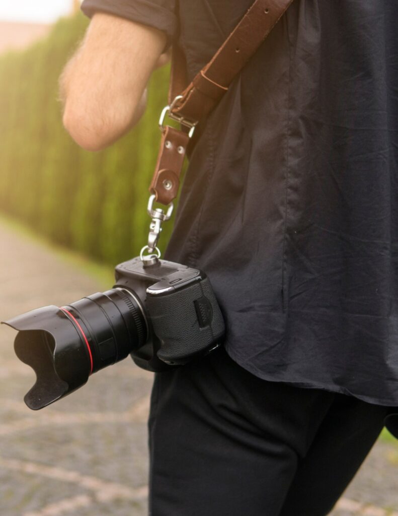 wedding photographer with a digital camera hanging from a strap by his hip