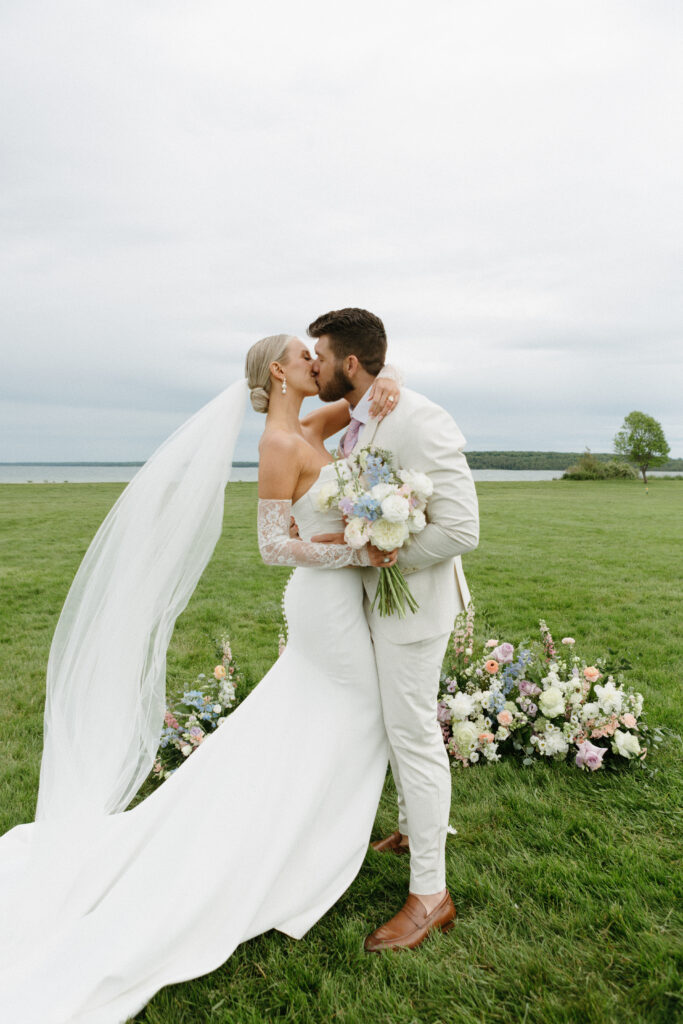 newly married husband and wife sharing a kiss on Mackinac Island in Michigan