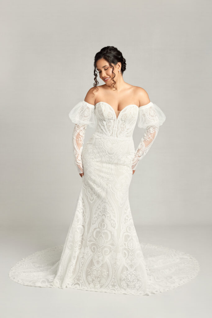 Clover w/Sleeves— a full lace with minimal sparkle fitted gown. Has full lace poof sleeves