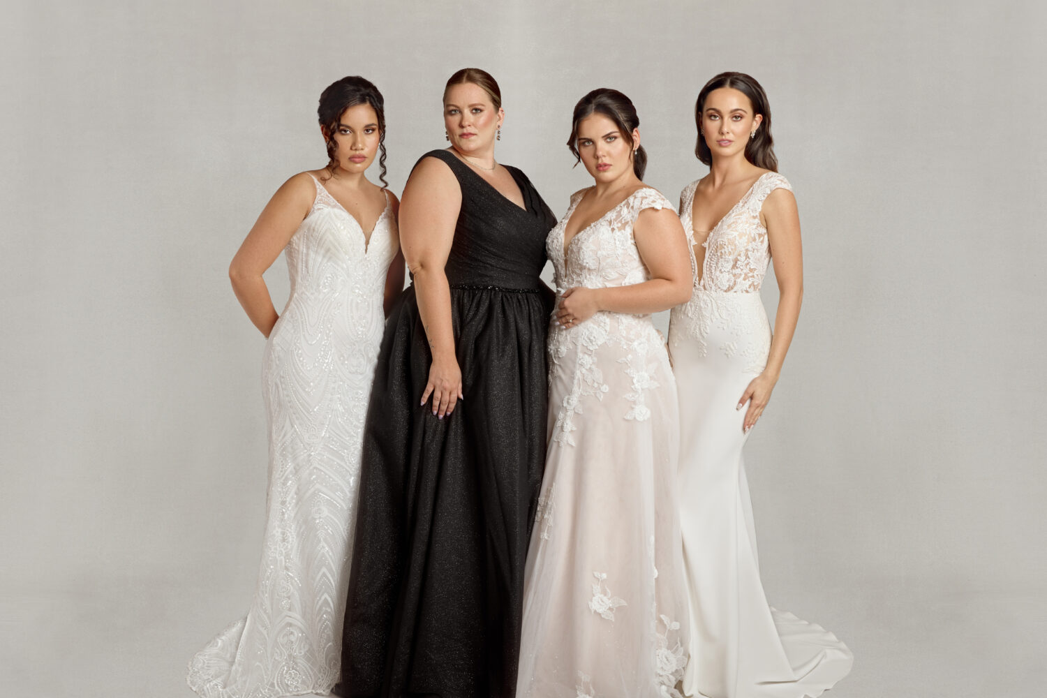 Four brides to be posing together in their wedding dresses of all styles including black wedding dresses.