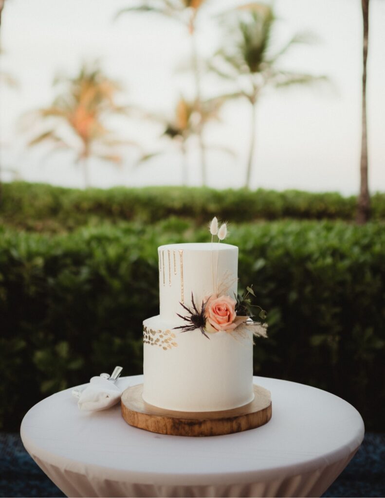 a sleek, elegant white wedding cake with gold and floral details