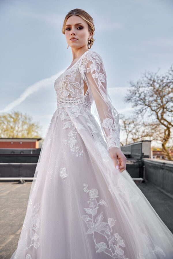 Stunning bride to be modeling one of The Wedding Shoppe's western wedding dresses. The lace long sleeve wedding dress has floral detailing throughout.