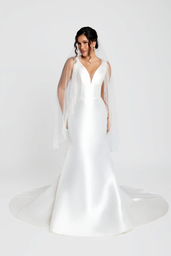 Bride to be wearing a classic wedding dress with a fit and flare style and a deep v cut neckline.