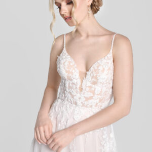 Shy bride wearing a spaghetti strap wedding dress with a deep v cut neckline and floral detailing on the bodice that flows down onto the flowy, tulle skirt.