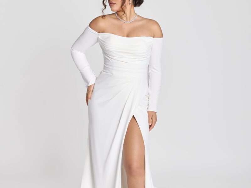 Gorgeous bride wearing a form fitting, off the shoulder, long sleeve wedding dress with a slit in one thigh.