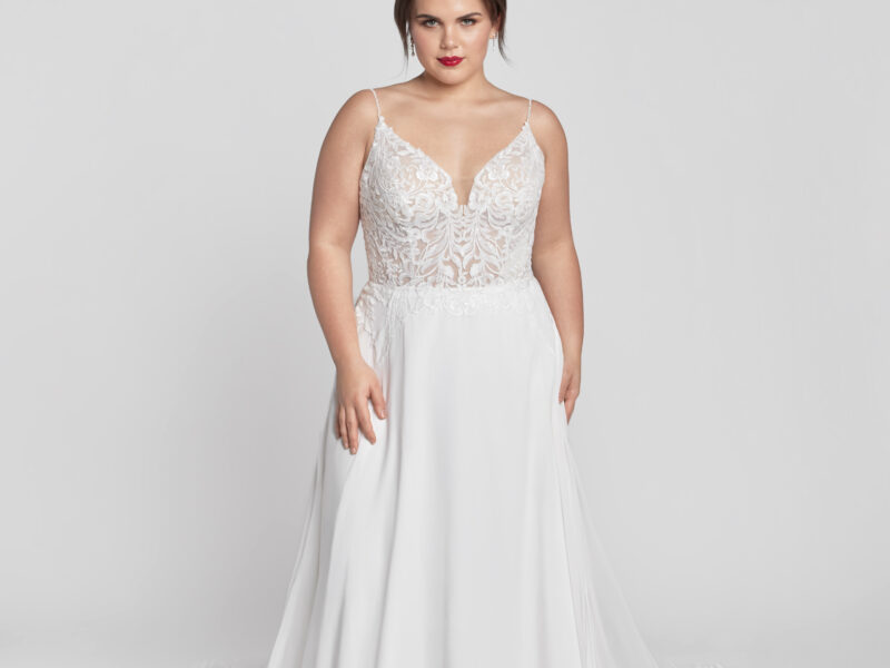 Plus size bride to be wearing a spaghetti strap wedding dress with lace appliques on the bodice and a simple flowing skirt.