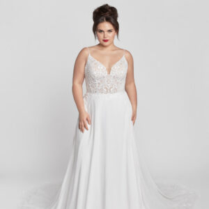 Plus size bride to be wearing a spaghetti strap wedding dress with lace appliques on the bodice and a simple flowing skirt.