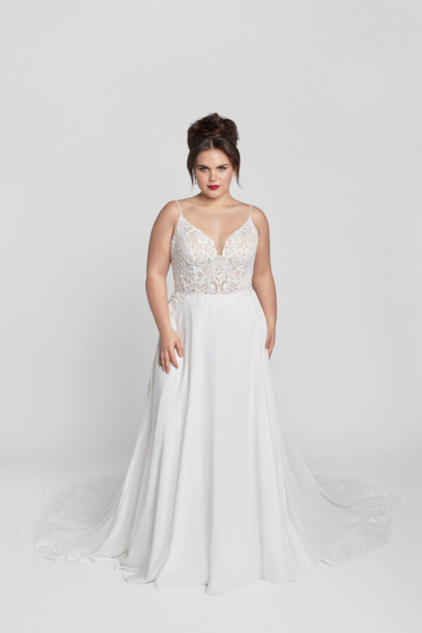 Plus size bride to be wearing a spaghetti strap wedding dress with lace appliques on the bodice and a simple flowing skirt.