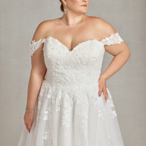 Plus size model wearing her wedding dress with tulle skirt and floral detailing on the bodice and off the shoulder sleeves.