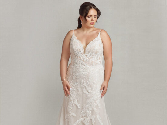 Bride to be wearing a boho wedding dress with spaghetti straps and floral lace appliques throughout.