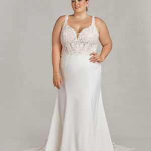 Confident bride wearing a floral embroidered wedding dress and standing with her hand on her hip.