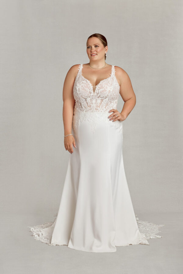 Confident bride wearing a floral embroidered wedding dress and standing with her hand on her hip.