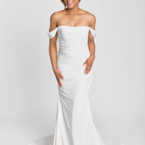 A smiling bride to be wearing an off the shoulder sleeve wedding dress with a ruched bodice and simple skirt.