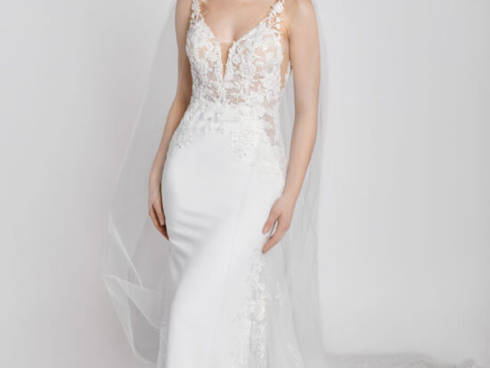 Confident bride to be wearing a wedding dress made of floral lace with spaghetti straps and a star train spread around her.