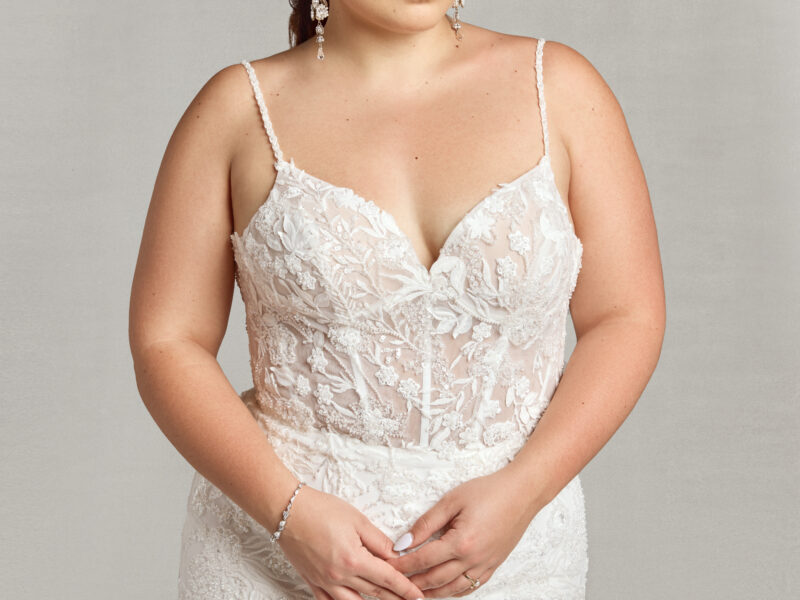 A boho style wedding dress worn by bride to be looking over her shoulder. The dress has floral detailing and buttons down the back.