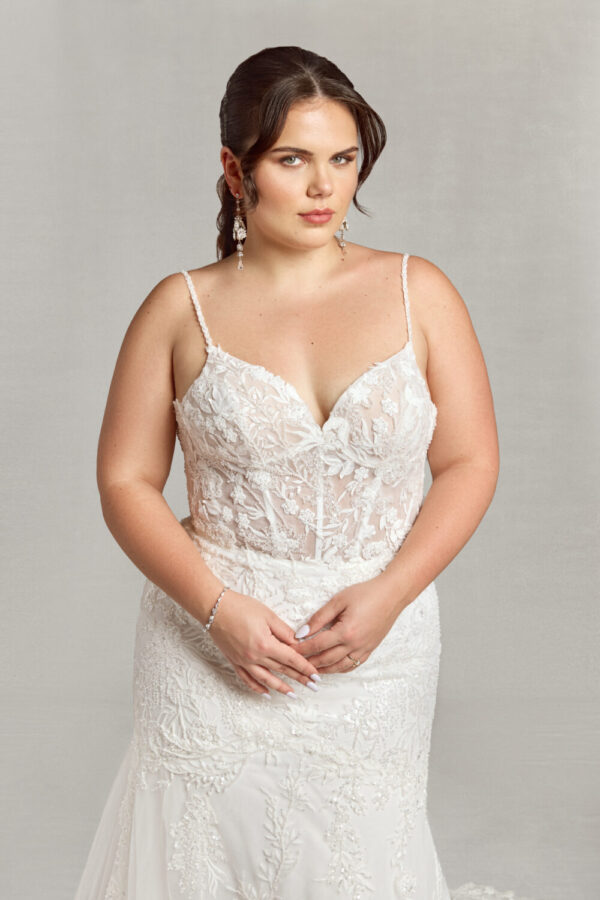 A boho style wedding dress worn by bride to be looking over her shoulder. The dress has floral detailing and buttons down the back.