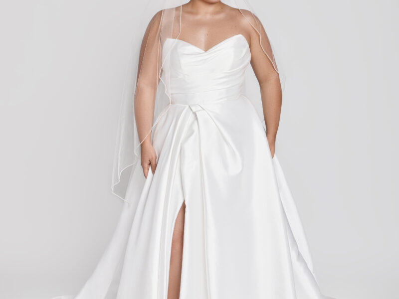 A timeless wedding dress style worn by a classic bride with a sweetheart neckline and basque waistline and slit up the thigh.