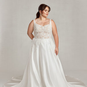 Confident plus size bride wearing a corseted wedding dress with see through bodice and shimmering, floral lace.