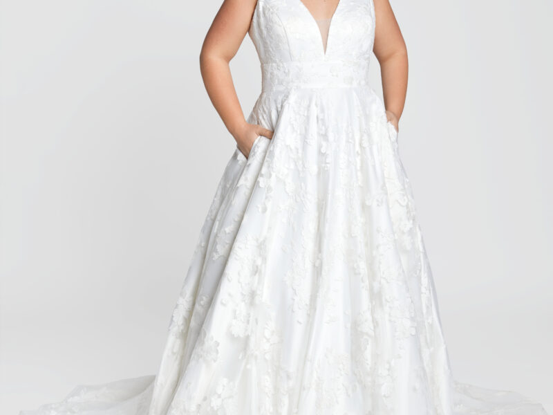 Modest wedding dress with a simple v cut neckline and patterned skirt being worn by bride to be.