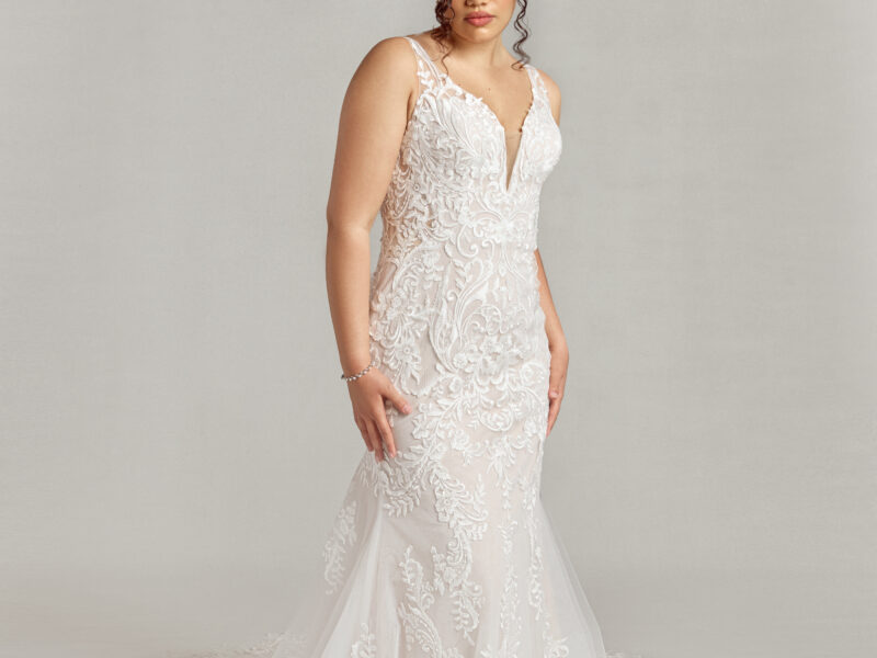 Stunning lace overlay wedding dress with a deep v cut neckline and a fit and flare shape worn by a confident bride.