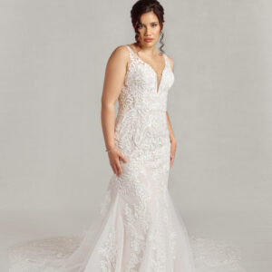 Stunning lace overlay wedding dress with a deep v cut neckline and a fit and flare shape worn by a confident bride.