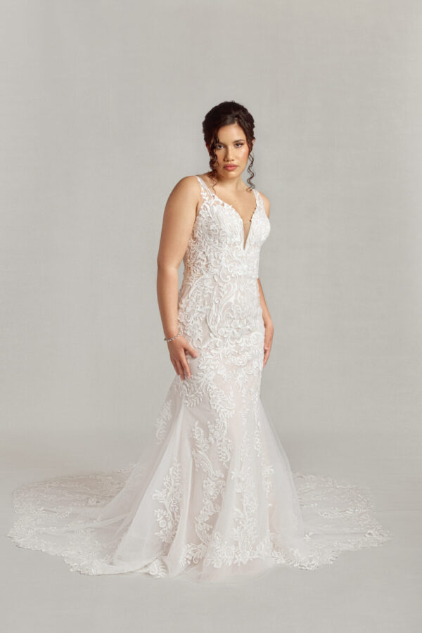 Stunning lace overlay wedding dress with a deep v cut neckline and a fit and flare shape worn by a confident bride.