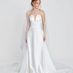 Simple wedding dress with a deep v cut neckline and simple, full skirt worn with a simple, long veil.