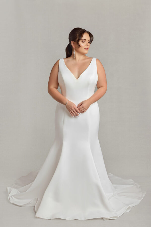 Stunning bride to be modeling a simple v cut wedding dress in a fit and flare shape.