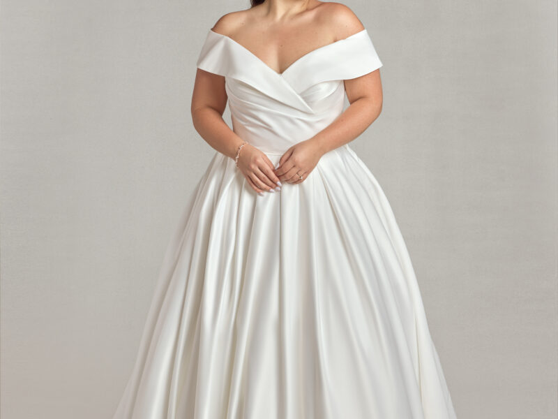 Traditional plus size bride modeling an off the shoulder sleeve wedding dress.