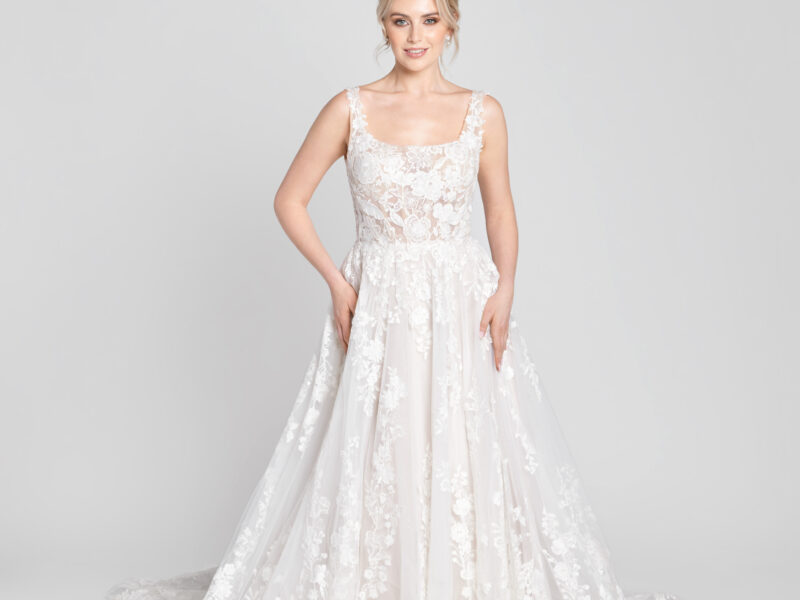 Sweet bride to be wearing a scoop neck wedding dress with floral detailing on the bodice flowing onto the multilayered skirt and lace train.