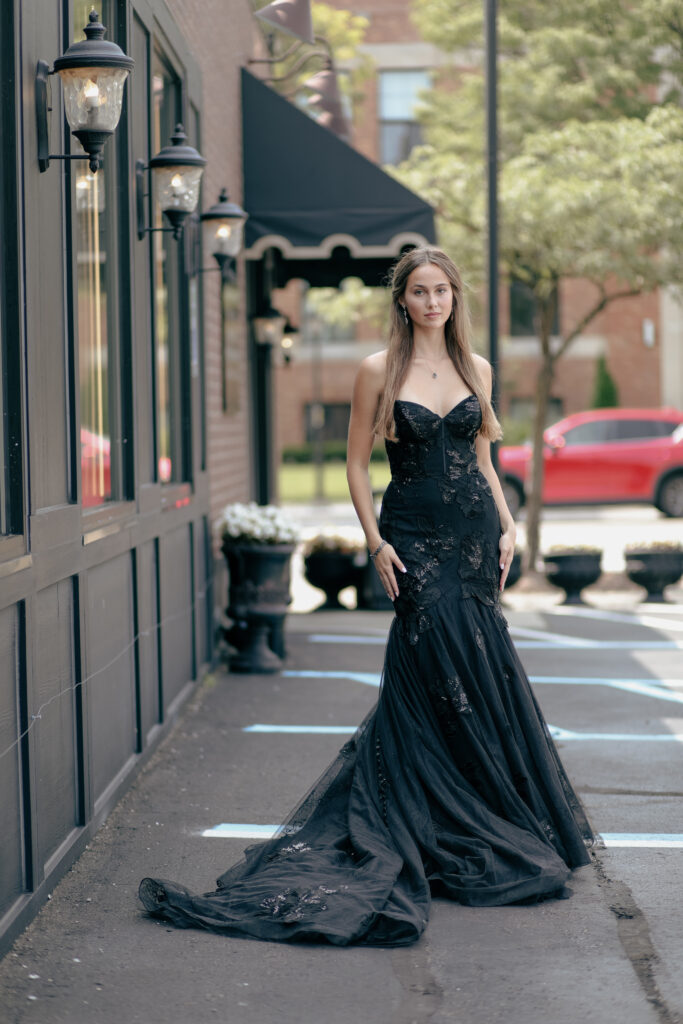 A young bride standing on a Michigan street in a black wedding gown with a medium train.