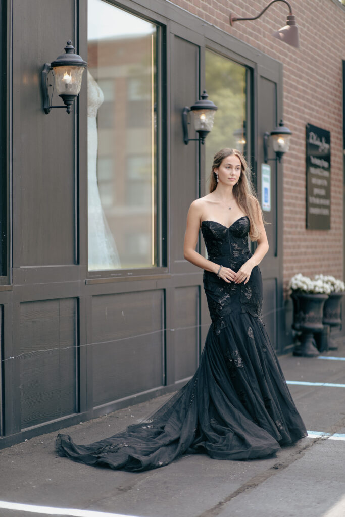 A young bride standing on a Michigan street in a black wedding gown with a medium train.