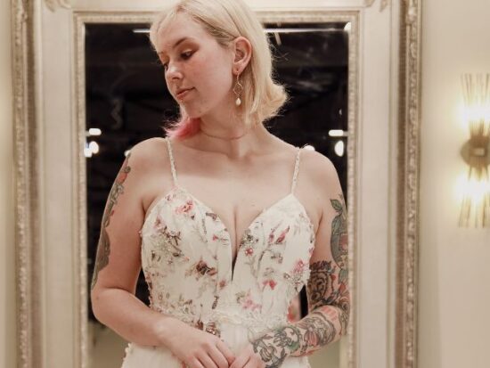 Close-up of a bride in a pastel floral gown, reflecting thoughtfully in a boutique mirror.