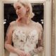 Close-up of a bride in a pastel floral gown, reflecting thoughtfully in a boutique mirror.