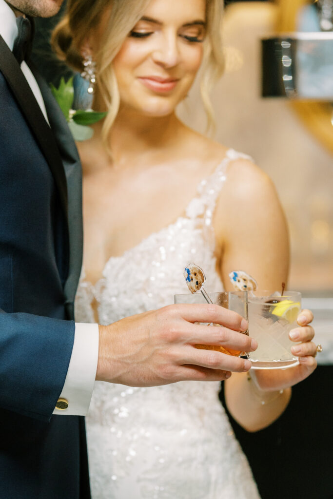 Newlyweds toast with cocktails adorned with dog-shaped stirrers at their wedding.