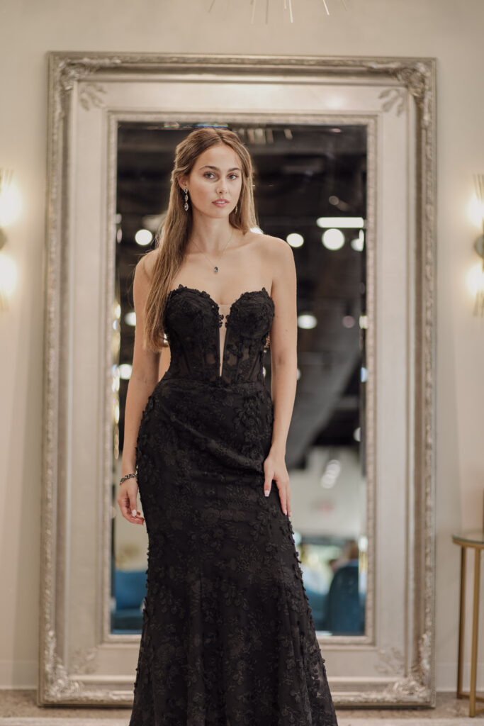 A bride wearing a strapless black wedding dress, in front of a mirror at a Michigan wedding shop.