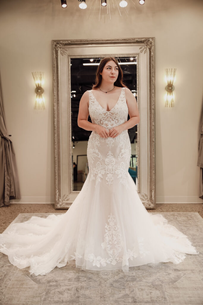 Detailed view of a bride's wedding dress train with elaborate lace and floral patterns in a bridal boutique.