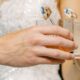 Detailed view of a couple’s hands clinking glasses with playful dog stirrers.