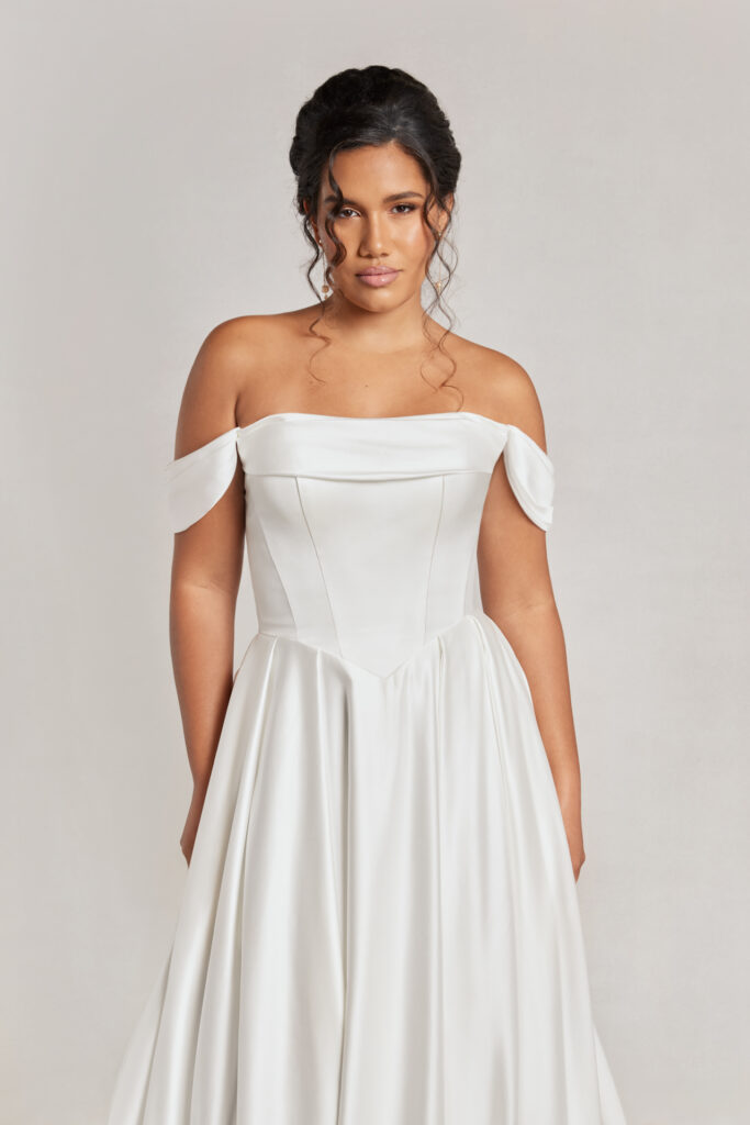 Bride in a simple off-shoulder basque waist gown, looking serene.