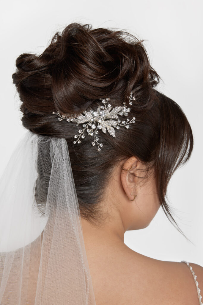 Bridal hairstyle with an intricate silver hairpiece and attached veil, back view.