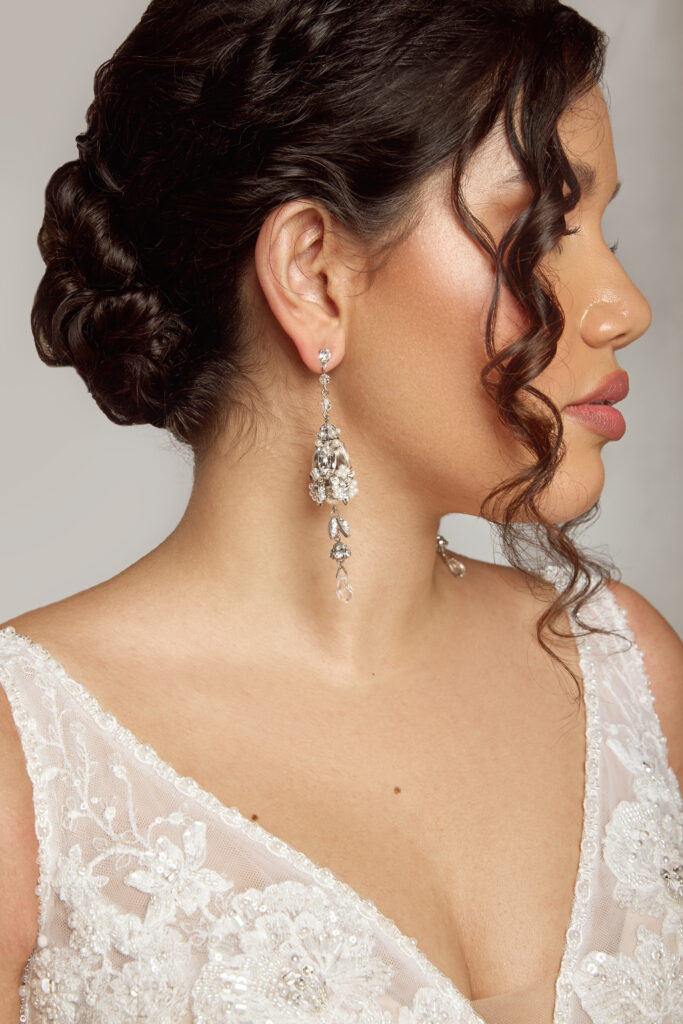 Close-up of a bride with elegant drop earrings and a detailed updo hairstyle.